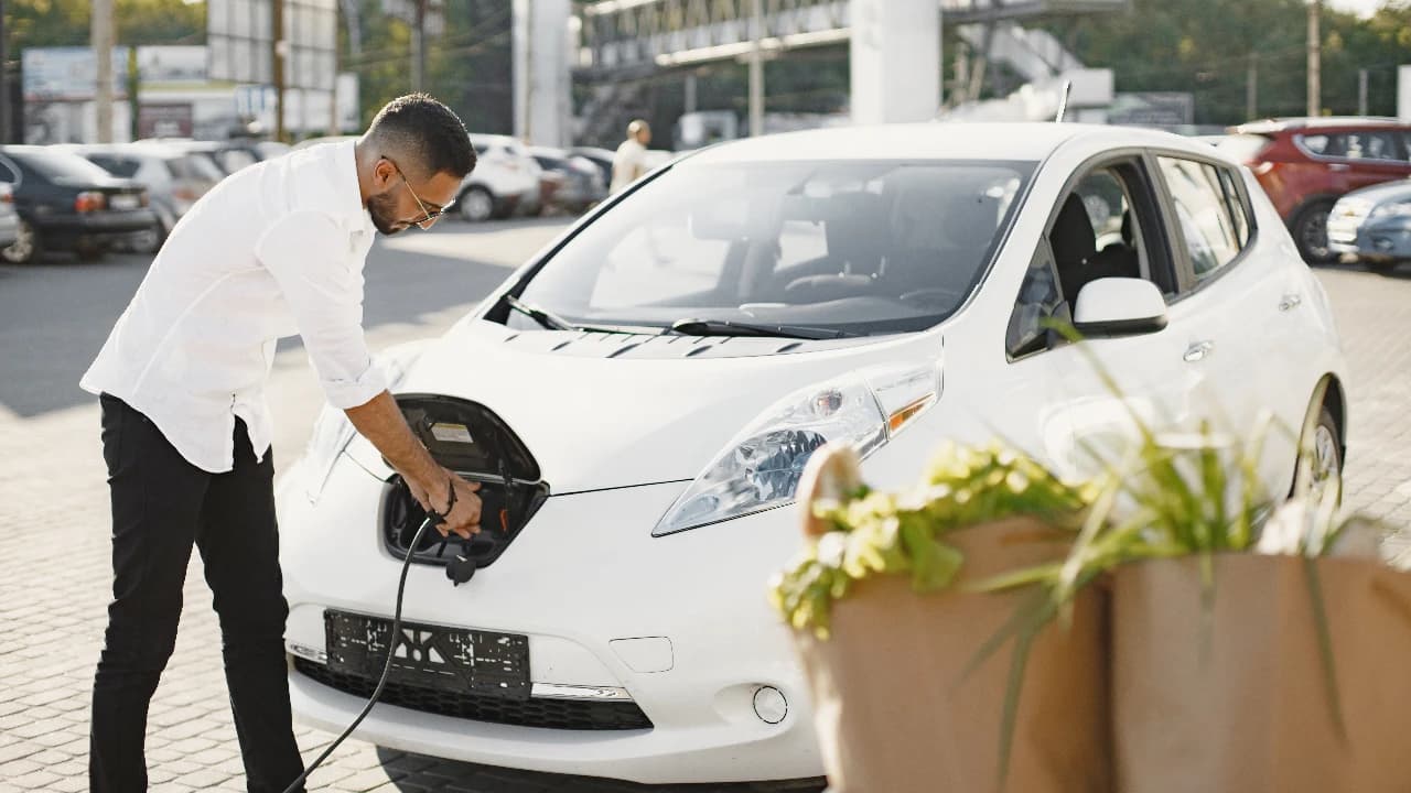 Jovem a carregar carro eléctrico ©Envato